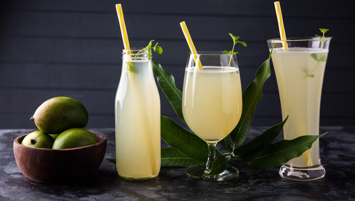 Mango juice OR Aam Panna or Panha in a transparent glass with whole green fruit,